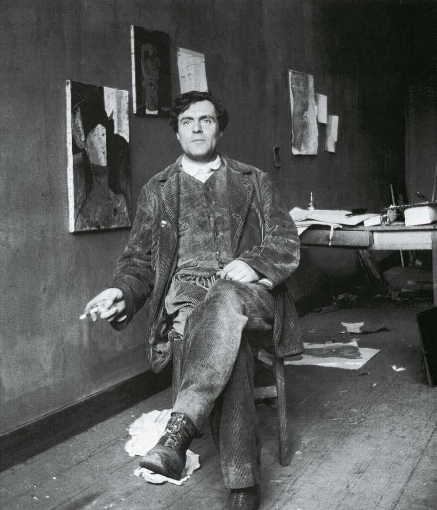 Amedeo Modigliani working in his art studio, surrounded by canvases and tools.